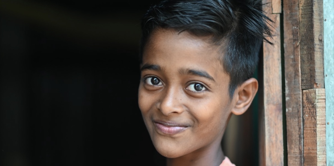 A smiling boy standing in a doorway